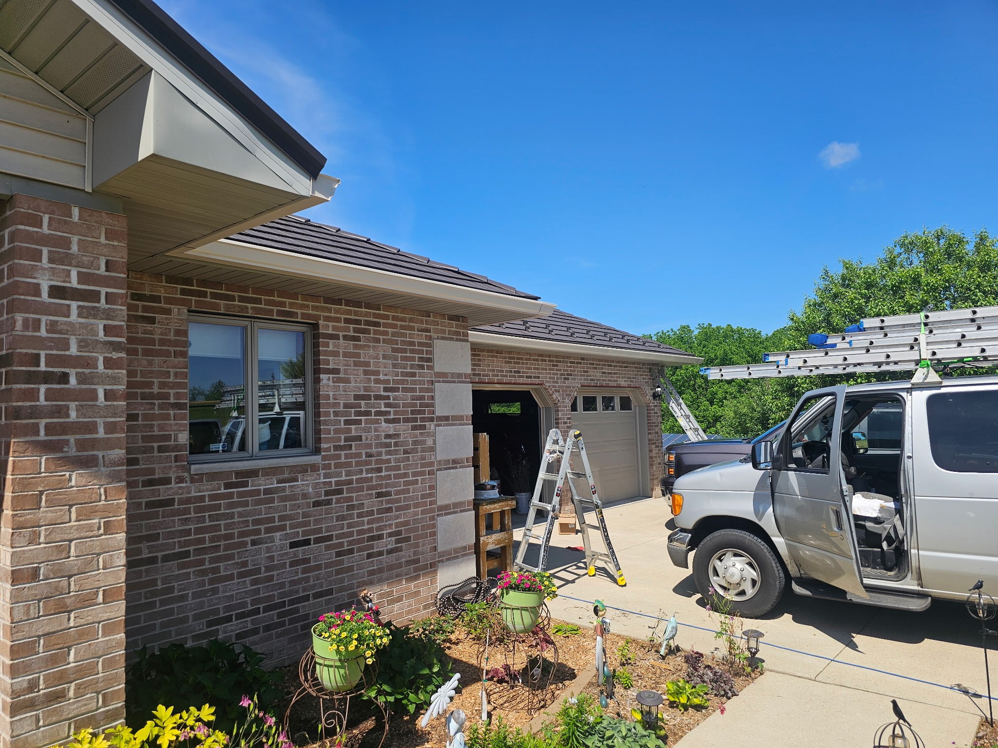 GutterForge gutter guard installation on brick home with ladders and work van