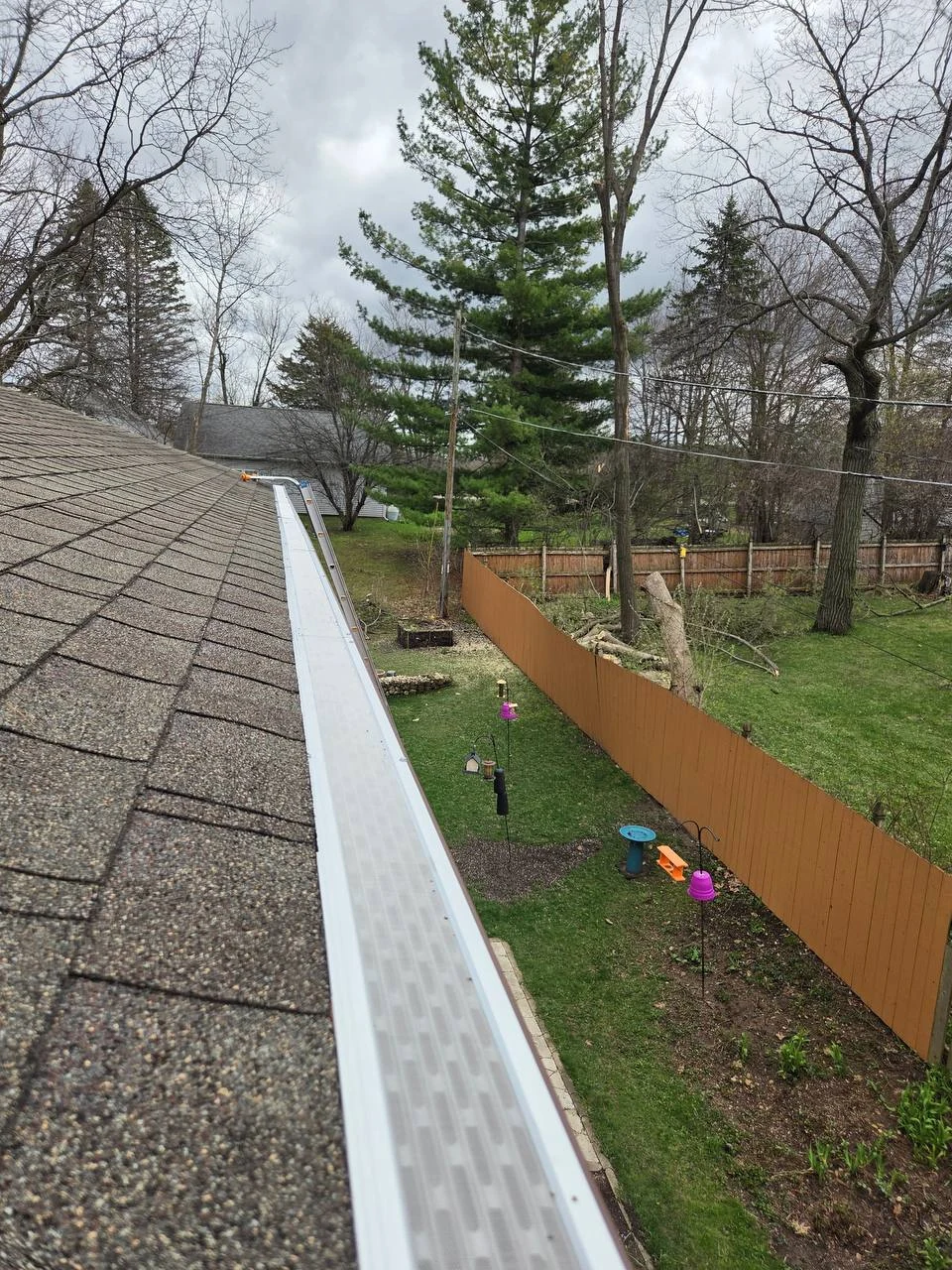 White micro-mesh gutter guard installed along a residential roofline by GutterForge