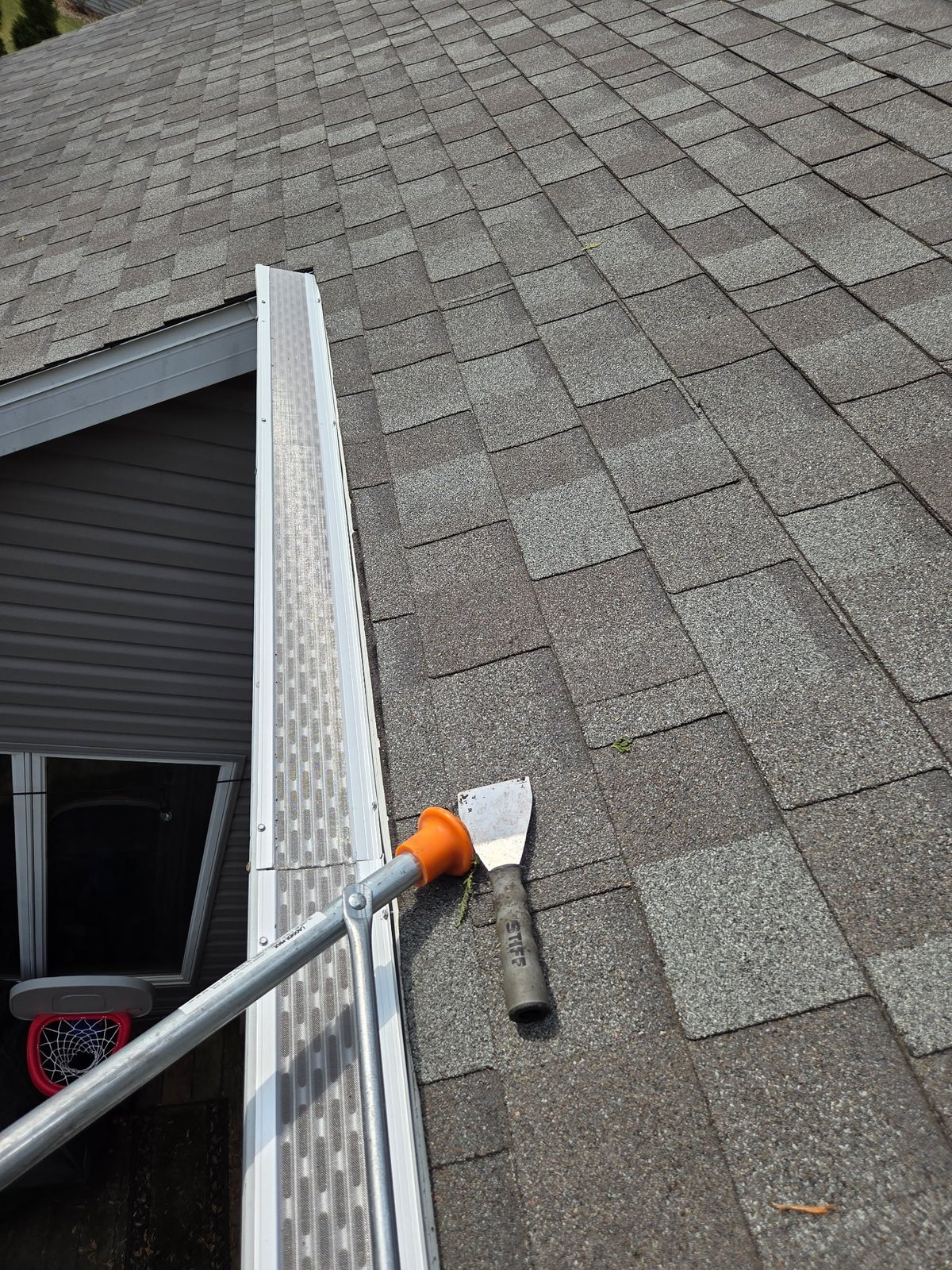 After photo showing a finished gutter guard installation with clean roofline and tools on the roof
